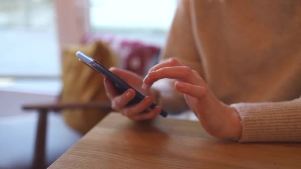 Primer plano de las manos de la mujer utiliza teléfono inteligente sentado en la mesa en la cafetería — Vídeos de Stock