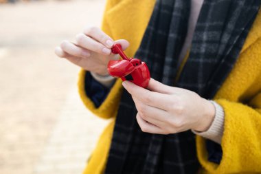 Kadın eli, şehir caddesindeki kırmızı çantadan kablosuz kulaklıkları çıkarır.