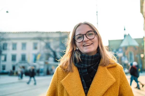 Mutlu gülümseyen genç kadın güneşli şehir caddesinde