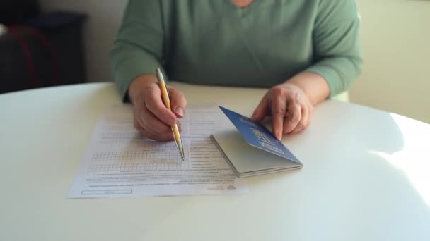 50 60s Kavkazská žena rukou psát perem v dokumentu PESEL na bílém stole na ministerstvu státní služby — Stock video