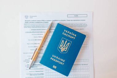 PESEL belgesi, Ukrayna pasaportu ve beyaz masa zemininde bir kalem.