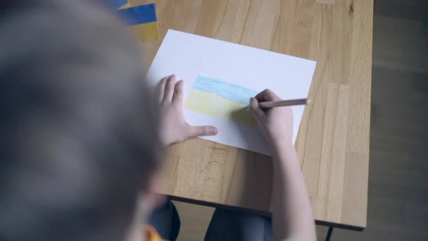 Детские руки с карандашом желтого и синего цвета рисуют украинский флаг дома — стоковое видео