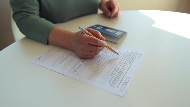 50 60s Καυκάσια γυναίκα χέρι γράψει με ένα στυλό στο έγγραφο PESEL σε λευκό τραπέζι στο τμήμα κρατικών υπηρεσιών — Αρχείο Βίντεο