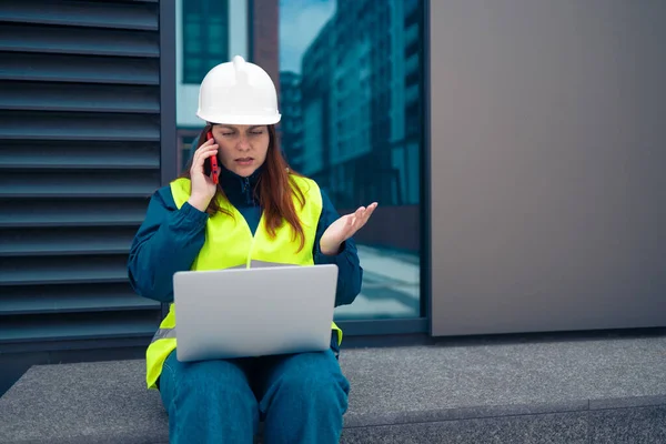 İnşaat alanında çalışan çalışkan kadın mühendis. Kendine güvenen mühendis telefonda konuşuyor ve mermi kovanı çalışmalarını gösteriyor. 