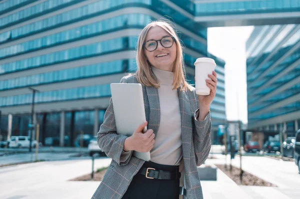 Diz üstü bilgisayarı olan ve biyo-kağıt kahve bardağını elinden alan Avrupalı sarışın, çekici iş kadını. Eko materyali. Sıcak içecekler için bir bardak. Metin için boş alan, maket yap
