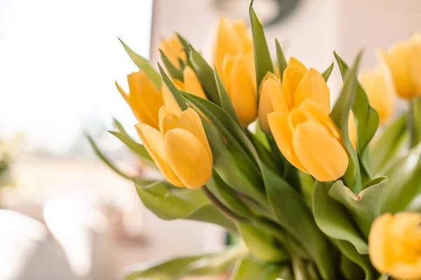 Vårblommor i vardagsrummets inredning. Bukett med färska gula tulpaner på träbord. Inredning. Vår eller helgdag koncept, 8 mars, Internationella kvinnodagen, födelsedag. — Stockfoto