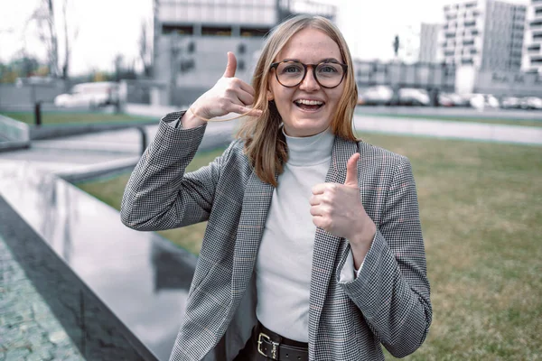 Call me. Portrait of pretty young blonde girl showing gesture call sing with fingers and toothy smile, looking at camera.