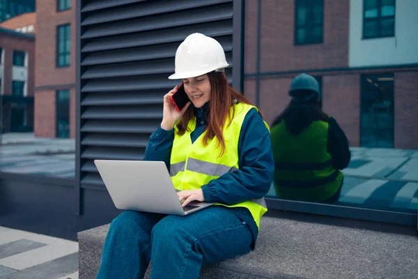 İnşaat alanında çalışan çalışkan kadın mühendis. Kendine güvenen mühendis telefonda konuşuyor ve mermi kovanı çalışmalarını gösteriyor. 