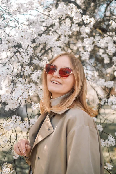 Çiçek açan bahar bahçesinde kokunun tadını çıkaran genç bir kadının portresi. Seyahat, özgürlük ve bahar tatili.