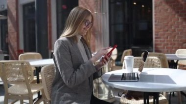 Yaratıcı iş kadını şık kıyafetler giyiyor. Çatı katındaki ofis binasının yanında akıllı telefon kullanıyor.