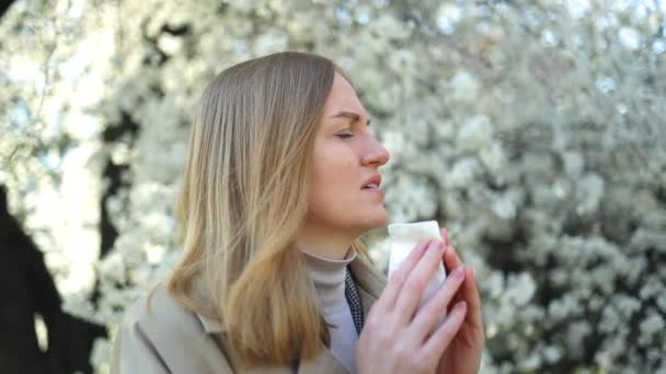 Young woman with handkerchief sneezing because of spring pollen allergy, seasonal allergy outdoors — Stok Video