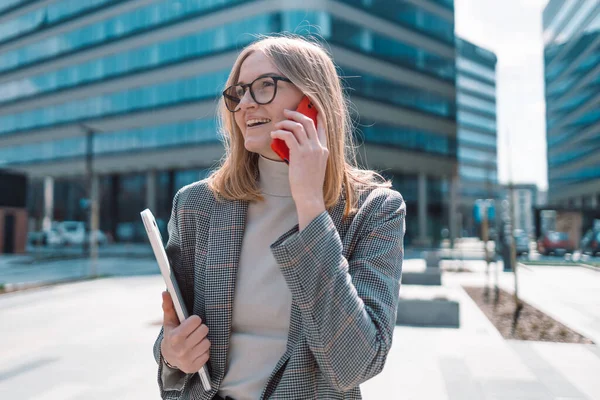 İş merkezinin önünde yürürken cep telefonuyla konuşan kendinden emin bir kadın.