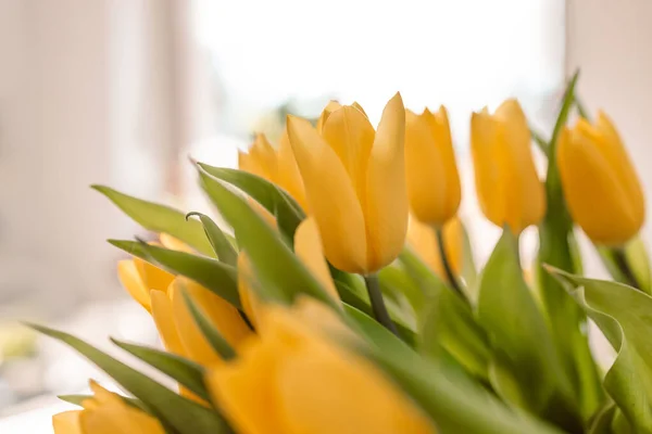 Oturma odasının iç tarafında bahar çiçekleri var. Ahşap masada taze sarı laleler. Ev dekoru. Bahar ya da tatil konsepti, 8 Mart, Uluslararası Kadınlar Günü, doğum günü. — Stok fotoğraf