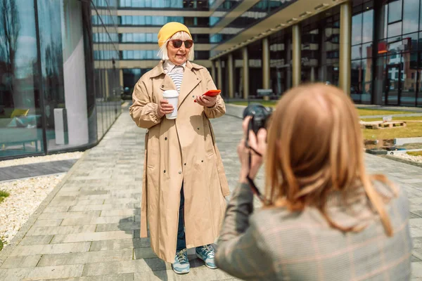 Uzman kadın fotoğrafçı, kamerayla dışarıda 50 'li yaşlarda sarışın bir kadının fotoğraflarını çekiyor. — Stok fotoğraf