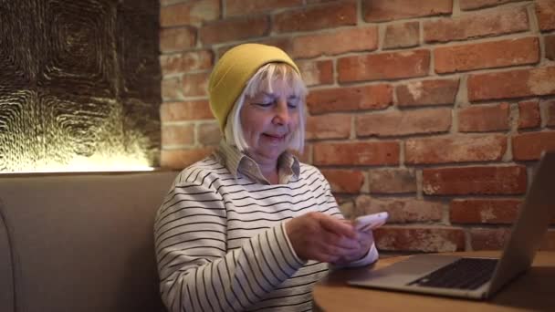 50s woman using smart phone for business, online shopping, transfer money, financial in coffee shop cafe over blurred background. — Vídeos de Stock