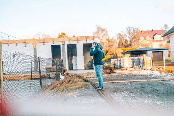 İnşaat mühendisi inşaat alanında elinde akıllı telefon tutan beyaz başlık takıyor. — Stok fotoğraf