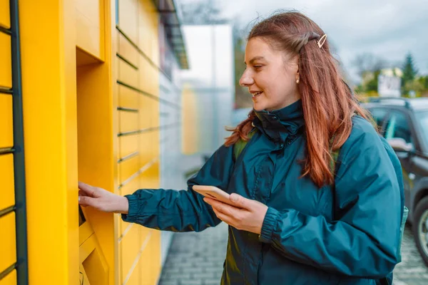 Woman picks up mail from automated self-service post terminal machine. Mail delivery, technology and post service concept
