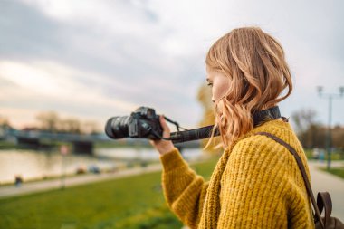 Photographer traveler 30s woman in style casual clothes take photo on video camera outdoor at city view. Copy space mockup. Hobie adventure concept
