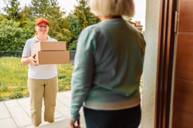 Postacı, evdeki kapının önünde müşteriye iki tane karton posta kutusu taşır. Ekspres dağıtım hizmeti, çevrimiçi alışveriş ve lojistik konsepti.
