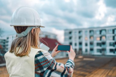 İnşaat alanında fotoğraf çeken kadın mimar inşaat çalışmalarının gidişatını kontrol ediyor.