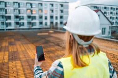 İnşaat alanında fotoğraf çeken kadın mimar inşaat çalışmalarının gidişatını kontrol ediyor.