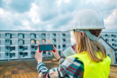 İnşaat alanında fotoğraf çeken kadın mimar inşaat çalışmalarının gidişatını kontrol ediyor.