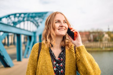 Çekici, beyaz saçlı, 30 'lu yaşlarda, sıradan elbiseli, gülümseyen, Spring City Caddesi' ndeki akıllı telefondan arayan bir kadın..