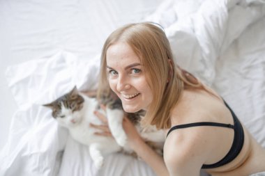 30 'lu yaşlarda, güzel beyaz bir kadının portresi. Evde beyaz, şirin bir kediyle yatakta uzanıyor ve sabahları eğleniyor. Yapılmamış yatakta tüylü bir hayvan. Kedi sever.. 