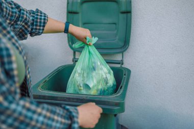 30 'lu yaşlardaki güzel Avrupalı bir kadın evin yakınındaki arka bahçedeki çöp kutusuna çöp atıyor.