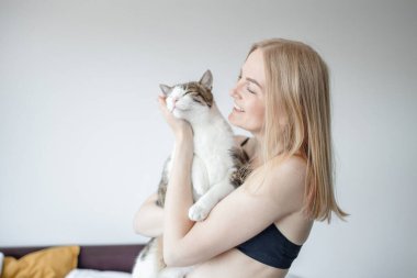 Kadın, evde kediye sarılıyor. Evde kal. Kendine dikkat et. Aşk, bakım, evlat edinme