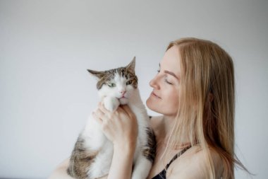 Kadın, evde kediye sarılıyor. Evde kal. Kendine dikkat et. Aşk, bakım, evlat edinme