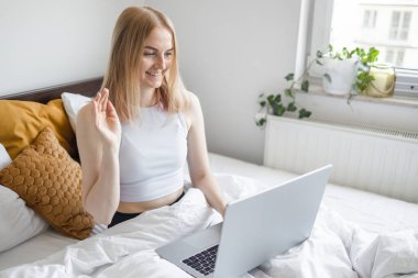 30 'lu yaşlarda mutlu bir bayan öğrenci, uzaktan çalışan, evde çalışan, yatakta dinlenen, bilgisayarla video görüşmesi yapan, Webinar izleyen, müşteriyle konuşan, konferansta iş arkadaşıyla konuşan...