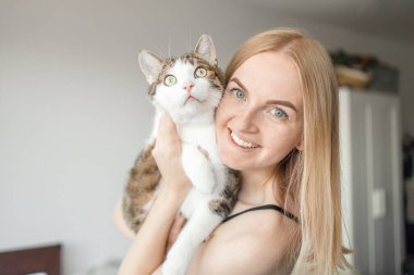 Kadın, evde kediye sarılıyor. Evde kal. Kendine dikkat et. Aşk, bakım, evlat edinme