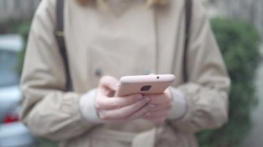 Avrupalı kadın elleri açık havada doğa koşullarına karşı akıllı telefon kullanıyor. 