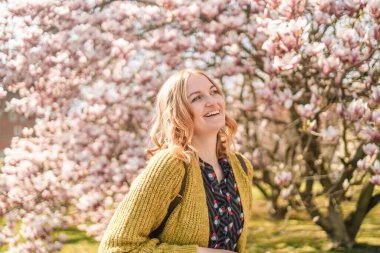 Moda tarzı romantik portre pembe manolyalar arasında poz veren 30 'lu yaşlarda güzel, güzel, sarışın bir kadının resmi. Çekici kız sana bakıyor ya da kameraya bakıyor.. 