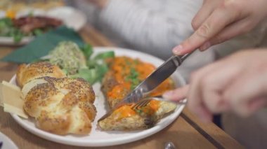 Caddedeki kafedeki ahşap masada omlet ve ıspanak yapraklarıyla sandviç kesen kadın videosu.