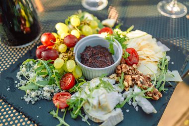 Peynir tabağı. Parmesan, maasdam, camembert, cheddar, gouda prosciutto, salam, meyve ve fındık. Lezzetli aperatifler. Boşluğu kopyala. 