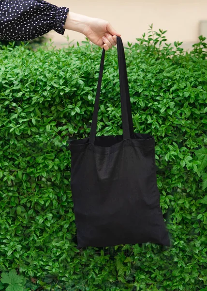 街の公園の背景に黒いテキスタイルエコモックアップバッグを持っている女性 ビニール袋や生態系の概念はない スペースのコピー — ストック写真