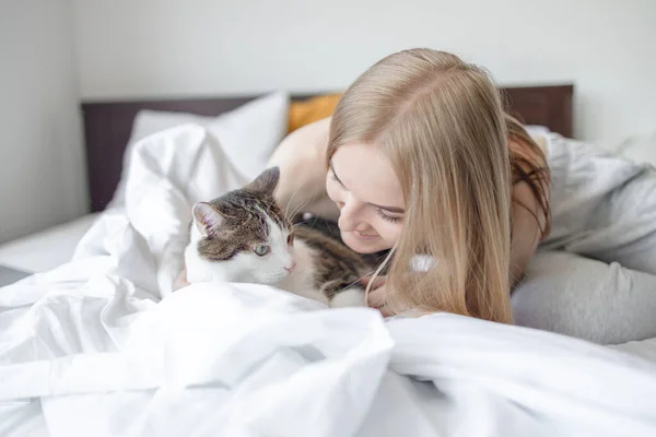 Female hugging cat in hands on the bed at home. Stay home stay safe. Love, care, adoption