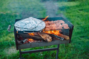 Baharatlı pirzola, çeşit çeşit lezzetli ızgara tavuk eti ve sebzeli sucuk. Kömürün üstünde mangal var. 