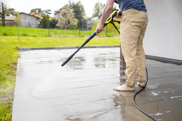 High water pressure cleaner on wet concrete terrace surface.