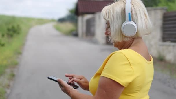 Beautiful Blonde Hair 50S Woman Listening Music Headphones Tapping Screen — Wideo stockowe