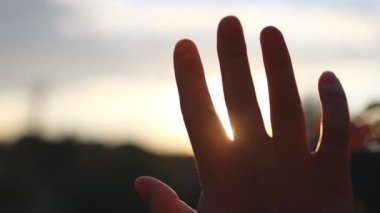 Person holding hand up to the light touching rays of warm sunshine through finger tips. Freedom in nature, and spirituality concept. 