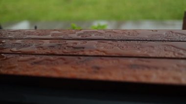 Rain drops on a park bench in close up view. Wooden bench on a rainy day. High quality FullHD footage