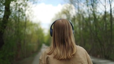Şehir parkındaki doğa ve açık hava müziğinin tadını çıkaran genç kızın yakın plan görüntüsü.