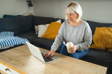 Not defterinde sarı saçlı güzel bir son sınıf öğrencisi var. Evdeki kanepede oturuyor. Teknolojik kadın konsepti 