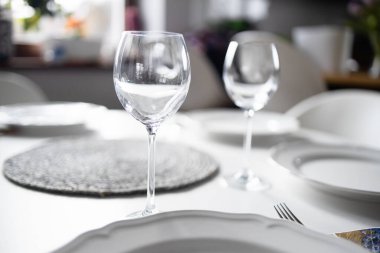 Oturma odasında boş bardaklar var. Beyaz masa örtüsü, tabaklar, kristal bardaklar. Yüksek kalite fotoğraf