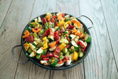  Yazın evin arka bahçesindeki ahşap bir masada tavada ızgara sebzeler. Vejetaryen, vejetaryen, mevsimlik, sağlıklı beslenme konsepti. 