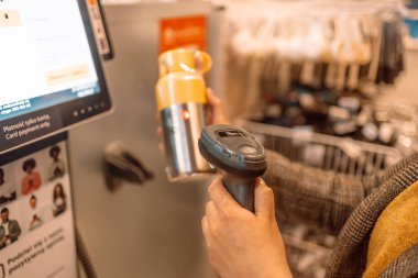 Woman hands customer scans thermos bottle at the self-service checkout in the grocery supermarket shop . High quality photo
