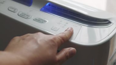 Button of air purifier. Caucasian woman hand trying to press a button on the portable air purifier machine in a bedroom. 4k footage